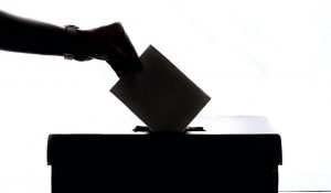 hand dropping paper inside a box as voting